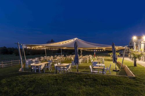 a marquee with tables and chairs in a field at night at Hotel Les Suites - Domaine de Crécy in Crecy la Chapelle