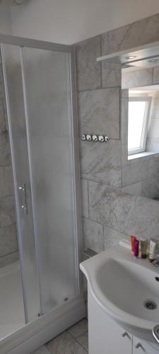 uma casa de banho branca com um chuveiro e um lavatório. em Astralis Factory Apartments-Marineta em Zagreb