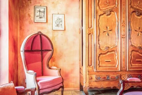 um quarto com uma cadeira vermelha e um armário de madeira em Hôtel Du Théâtre Centre Historique Parking Gratuit em Metz