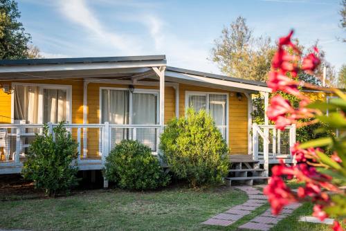 a yellow house with a porch and bushes at Club del Sole Vigna sul Mar Family Collection in Lido di Pomposa