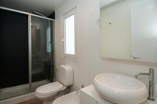 a white bathroom with a toilet and a sink at Club del Sole Vigna sul Mar Family Collection in Lido di Pomposa