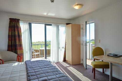 a bedroom with a bed and a desk and a balcony at Kaikoura Quality Suites in Kaikoura