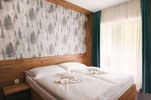 a bedroom with a bed with white sheets and bows at Apartmány Štiavnica & Ďurková - Galeria Apartments Jasná Lúčky in Demanovska Dolina