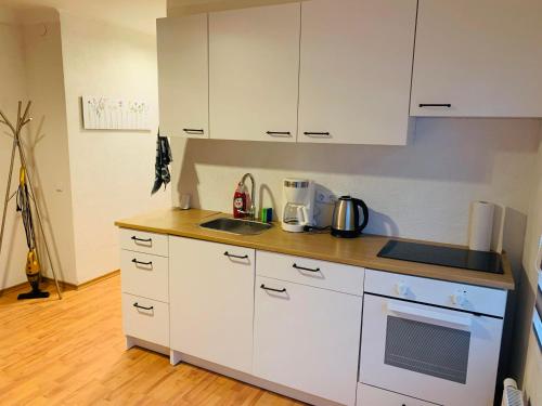 a kitchen with white cabinets and a wooden floor at Apartment Marielena in Püttlingen
