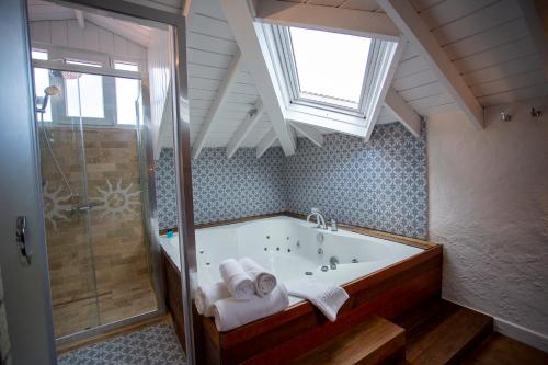 a bathroom with a tub with a shower and a window at Kokopelli Alacati in Alaçatı