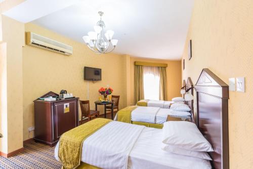 a hotel room with three beds and a television at Victoria Hotel in Dubai