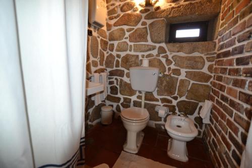 a stone bathroom with a toilet and a sink at Moinho de Estoraos in Ponte de Lima