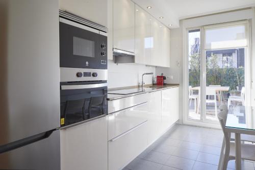 a kitchen with white appliances and a table and a window at Esnatuz - Basque Stay in San Sebastián
