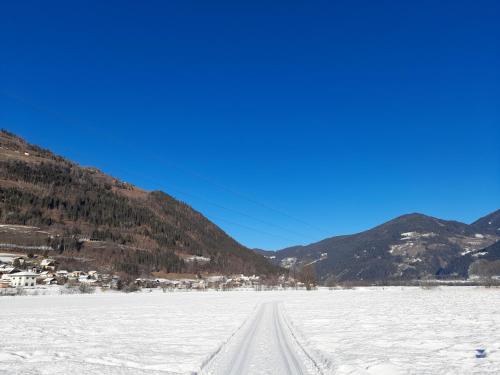 a road in the snow with mountains in the background at Ferienwohnungen Rosi in Kleblach