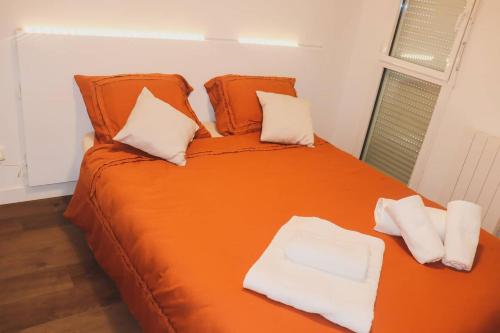 1 cama grande de color naranja con 2 almohadas en T3 au centre ville avec balcon, parking gratuit, en Quimper