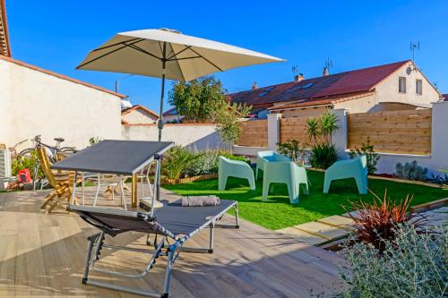 eine Terrasse mit einem Tisch, einem Sonnenschirm und Stühlen in der Unterkunft Le Cabanon de Virginie in Salin-de-Giraud