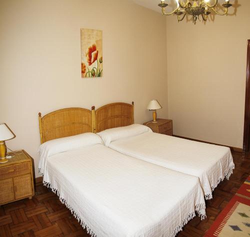 2 camas en un dormitorio con sábanas blancas en Apartamento en el corazón de Gijón con parking incluido, VUT 78, en Gijón