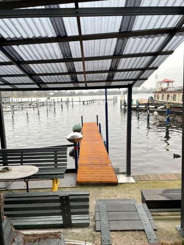 a dock with a bench and a wooden pier in the water at Pension am Tiefen See in Potsdam