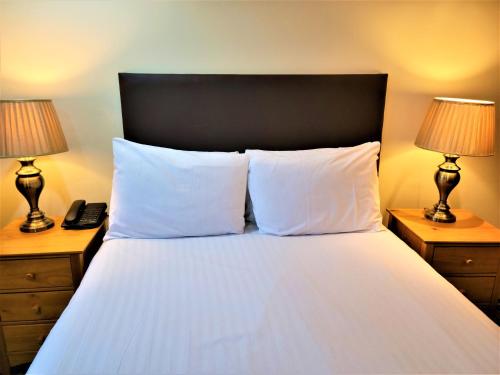 a bedroom with a bed with white sheets and two lamps at Grand Plaza Serviced Apartments in London