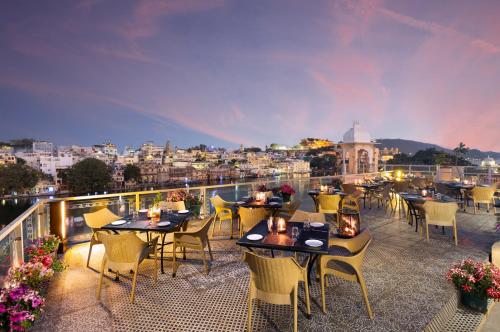 a restaurant with tables and chairs on a balcony at Hotel Sarovar On Lake Pichola in Udaipur