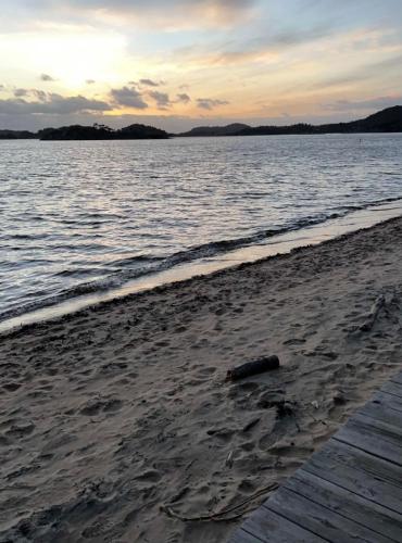 a log sitting on the beach next to the water at experience a fantastic summer house 2025 in Kristiansand
