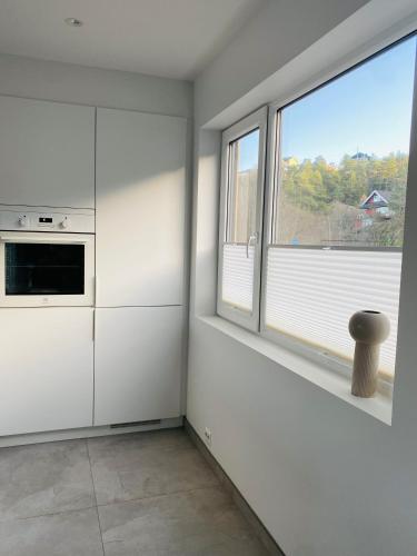 a kitchen with white cabinets and a window at experience a fantastic summer house 2025 in Kristiansand