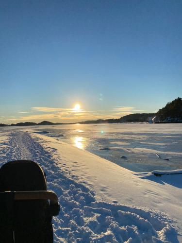 a snow covered beach with the sun in the background at experience a fantastic summer house 2025 in Kristiansand