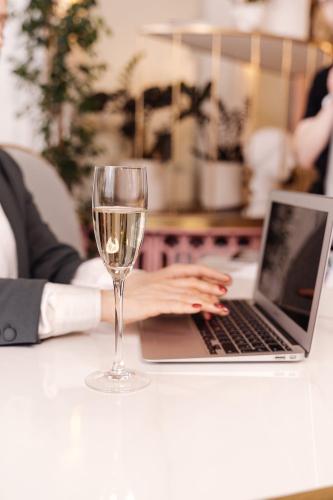a woman typing on a laptop with a glass of wine at Hotel & Restauracja Timberland in Orzesze