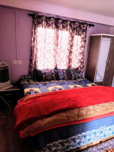 a bedroom with a large bed with a window at Pine Wood in Kotgarh