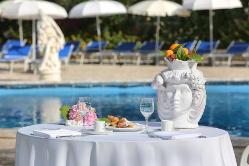a table with a vase and a plate of food at Sant Alphio Garden Hotel & SPA in Giardini Naxos