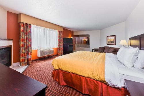 a hotel room with a large bed and a fireplace at AmericInn by Wyndham Muscatine in Muscatine