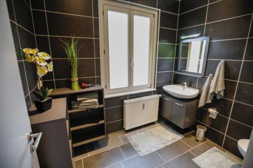 uma casa de banho em azulejos pretos com um lavatório e uma janela em Turis Ferienwohnung 65-1 em Triberg