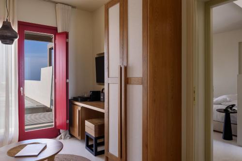 a bedroom with a door open to a room with a balcony at Potnia Theron Suites in Akrotiri