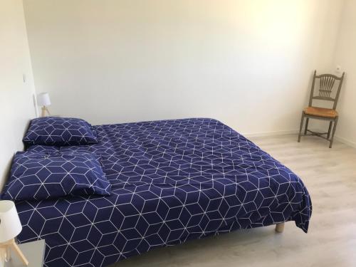 a bedroom with a bed with a blue comforter and a chair at les gîtes d'en Julio in Puylaurens