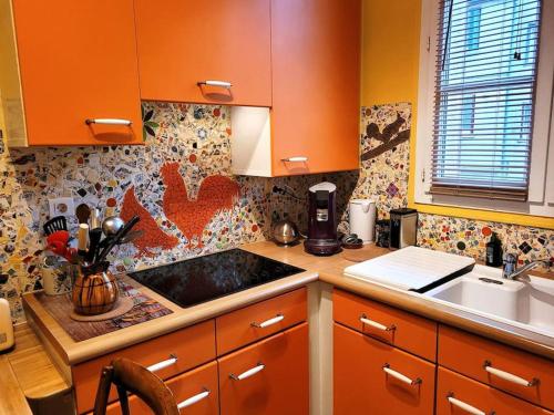 uma cozinha com armários laranja e um lavatório em Zassiettes et titin em Dijon