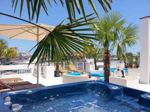 a swimming pool with a palm tree and chairs at Harisis Apartments in Olympic Beach