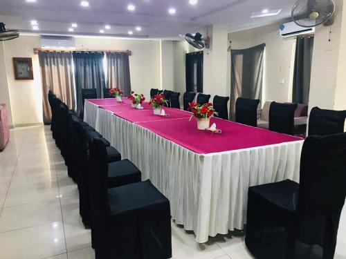 una mesa larga en una habitación con sillas negras y mantel rojo en Plaza Inn Hotel, en Rahimyar Khan