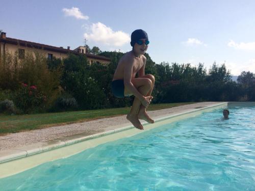 a young boy jumping into a swimming pool at Agriturismo Lupo Vecchio in Grosseto