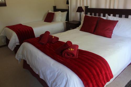 two beds in a hotel room with red towels on them at The Golden Grape B&B in Lutzville