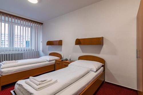 two beds in a small room with a window at Hotel Garni VŠB TUO in Ostrava