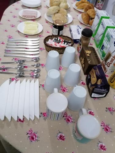 Una mesa cubierta con tazas y platos blancos y pasteles. en 9Arches, en Vila Nova de Poiares