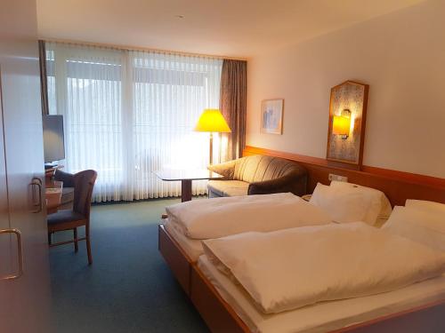 a hotel room with two beds and a couch at Hotel Graf Eberhard in Bad Urach