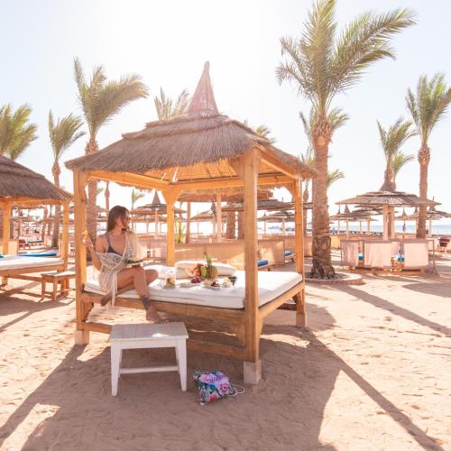 a woman sitting in a gazebo on the beach at Pickalbatros Palace - Aqua Park Hurghada in Hurghada