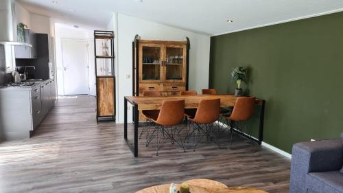a kitchen and dining room with a wooden table and chairs at de4SeiZoentjes in Schoonebeek