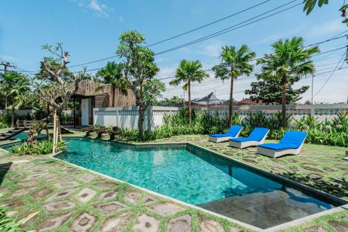 a swimming pool with two blue lounge chairs and trees at The Wave in Canggu