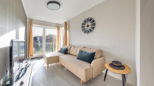a living room with a couch and a clock on the wall at Hel Żeromskiego, Sun & Snow in Hel
