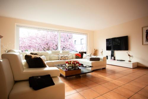 a living room with white furniture and a large window at Hotel Am Sportpark in Duisburg