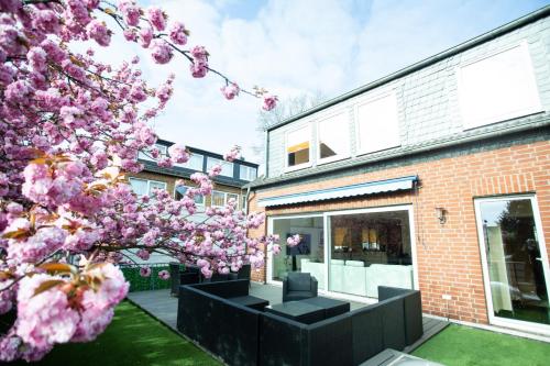 a house with a flowering tree in front of a building at Hotel Am Sportpark in Duisburg