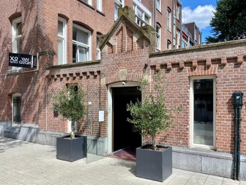 a brick building with two potted trees in front of it at Hotel Van Gogh in Amsterdam