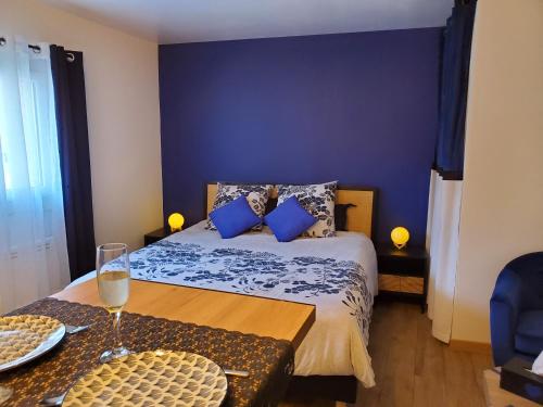 Un dormitorio con una cama con paredes azules y una mesa. en Jacuzzi privatif dans maison de village au calme en Flaviac