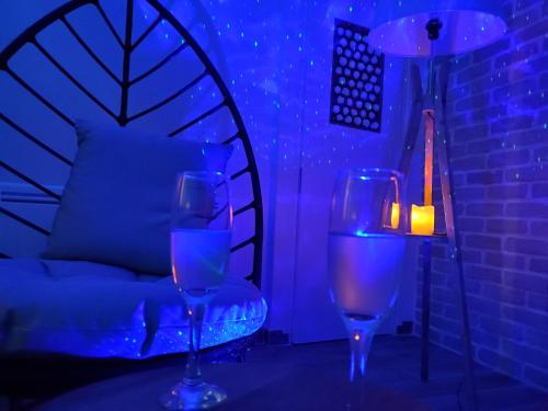 two wine glasses sitting on a table with a lamp at Jacuzzi privatif dans maison de village au calme in Flaviac