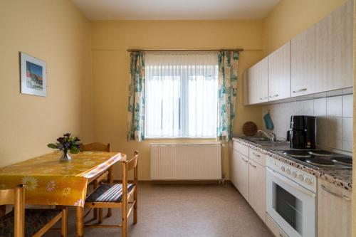a kitchen with a table and a table and a window at Ferienwohnung 1, Waldesruh Dierhagen in Dierhagen