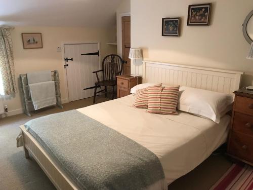 a bedroom with a bed with pillows and a chair at The Long House in Cirencester