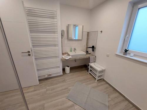 a white bathroom with a sink and a mirror at Ferienwohnung Königsquelle in Bad Wildungen