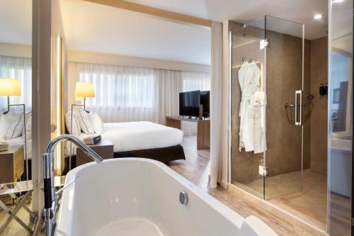 a hotel room with a tub and a bedroom at Melia Lebreros in Seville
